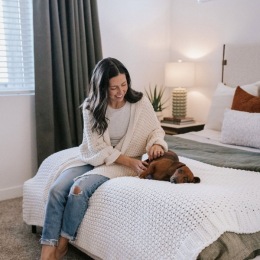a person petting a dog on a bed