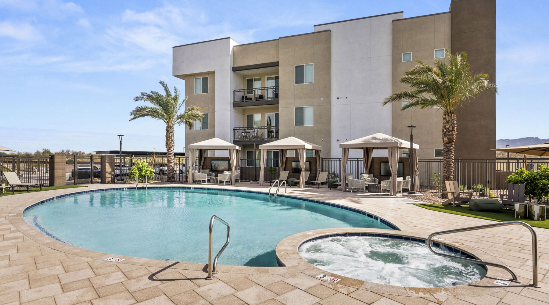 resort style pool with seating with a building behind it